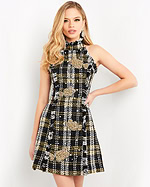 Model wearing M03286, an A-line knee-length dress with high neckline and sleeveless design in multi-color plaid with gold fish motifs.