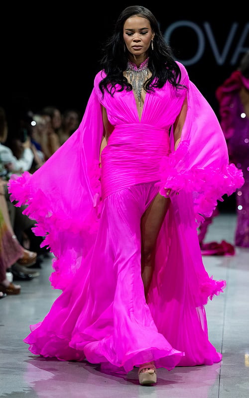 model wearing S36352 vibrant pink gown with plunging neckline and cape sleeves
