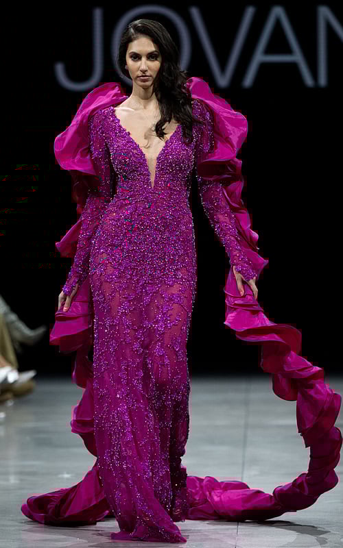 Model wearing Jovani S36413 fuchsia gown with beadwork and ruffled sleeves.