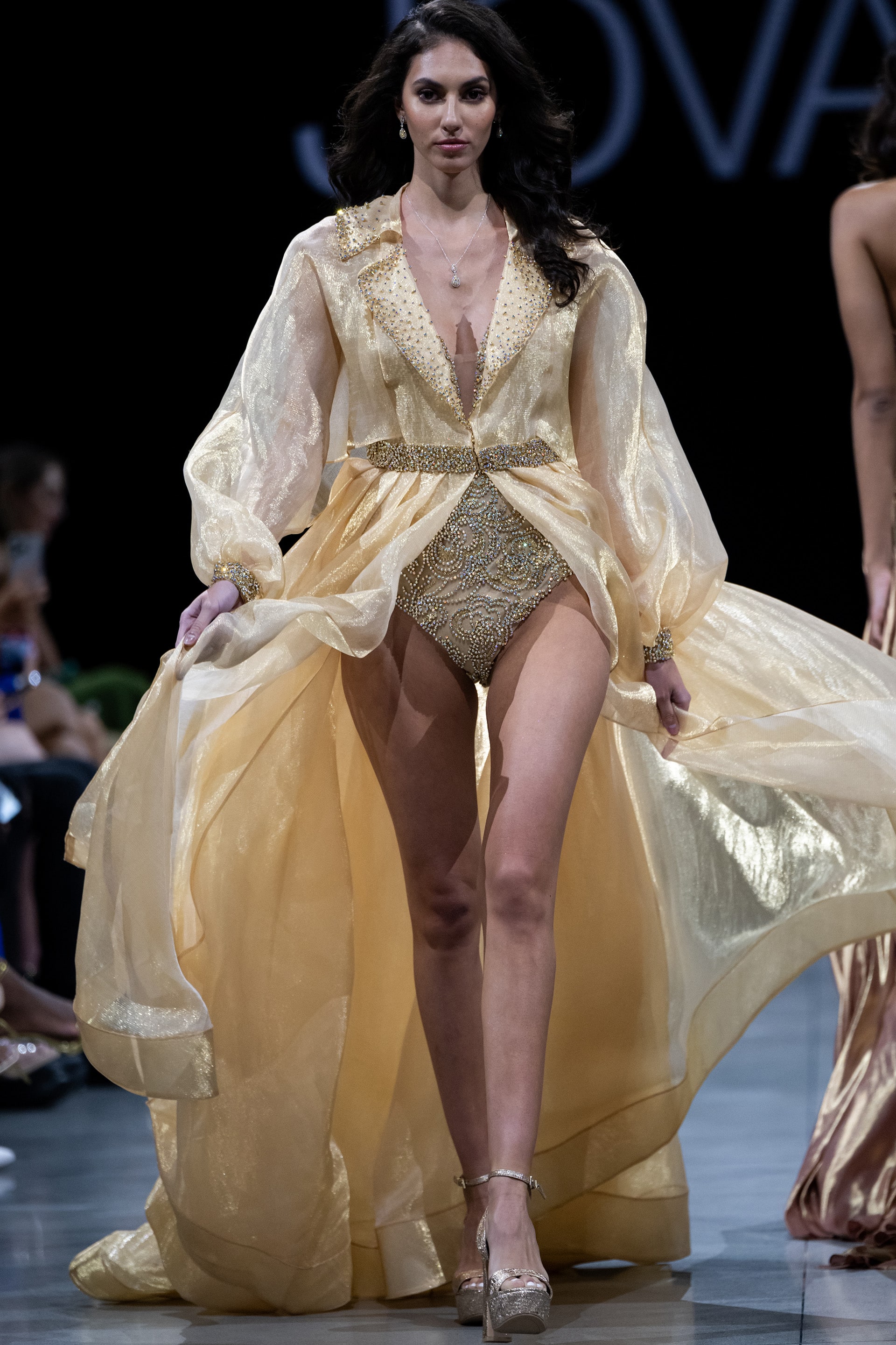 S38445.jpg model wearing Jovani S38445 gold dress with V-neckline and voluminous sleeves