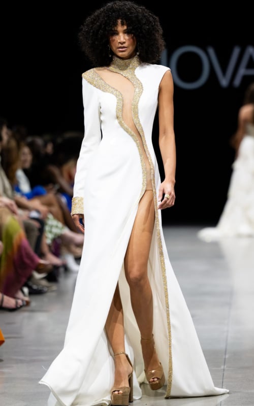 Model wearing Jovani S38446 white gown featuring a high neckline, embellishments, high slit, and full-length sleek design.