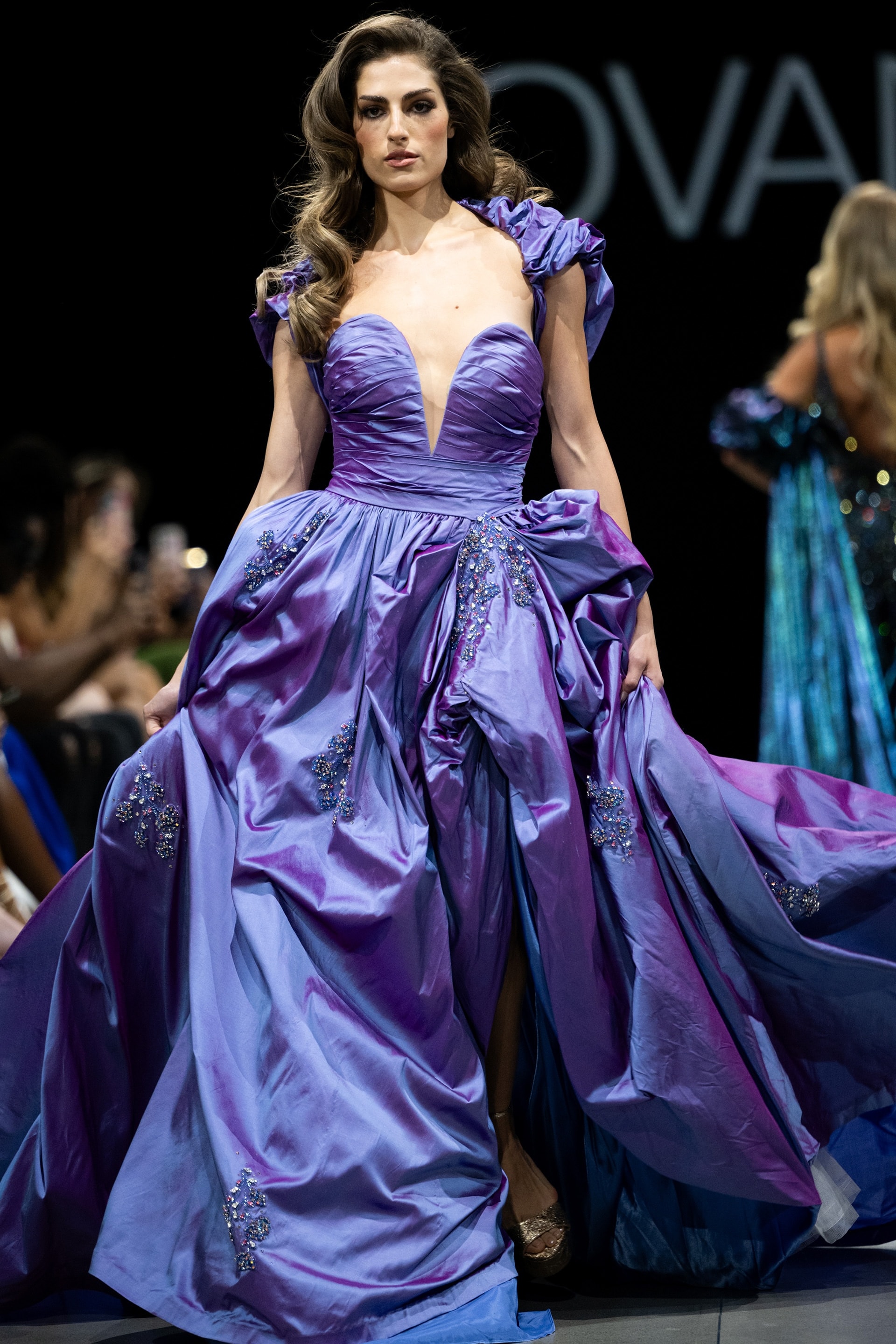 S39133.jpg Model wearing Jovani S39133 purple gown with deep V-neck and voluminous skirt