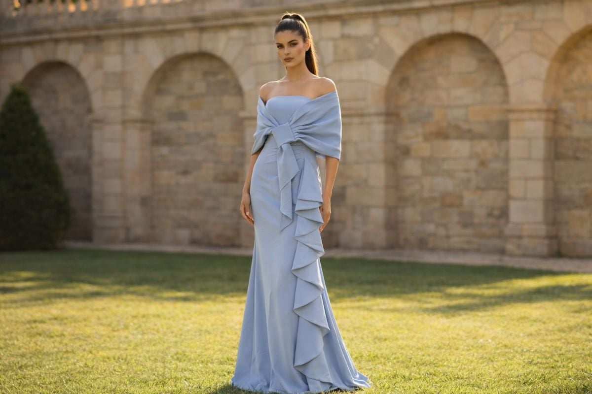 Dusty blue strapless evening gown with front knot shawl and vertical ruffle detail in a classical courtyard