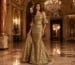 Woman in gold mermaid evening gown in luxury ballroom