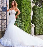 Model posing in Jovani JB07260 white dress, featuring a mermaid silhouette and intricate lace design