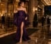 Woman in plum evening gown with matching stole arriving at luxury gala