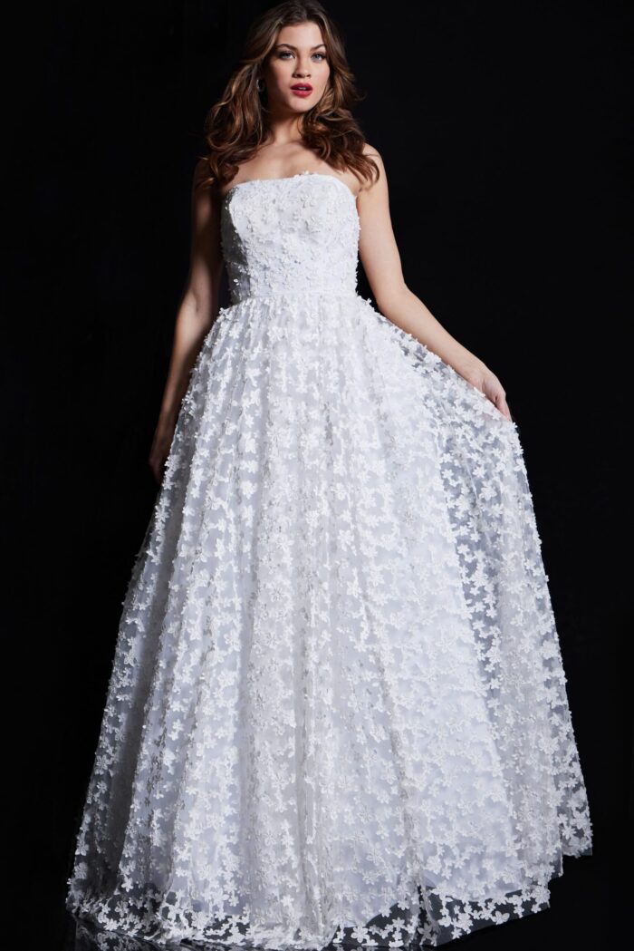 Model wearing Jovani 08536 ivory gown holding the skirt, showcasing floral lace details.